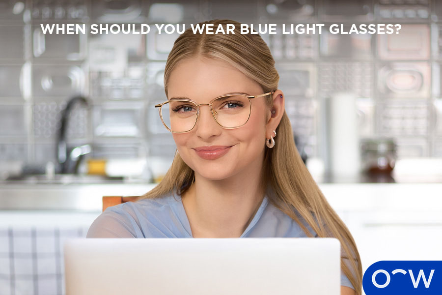 A younger person in front of a laptop screen while wearing blue light glasses.