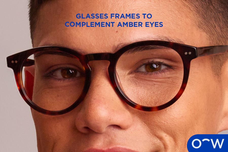 A man with amber colour eyes wearing tortoiseshell glasses.