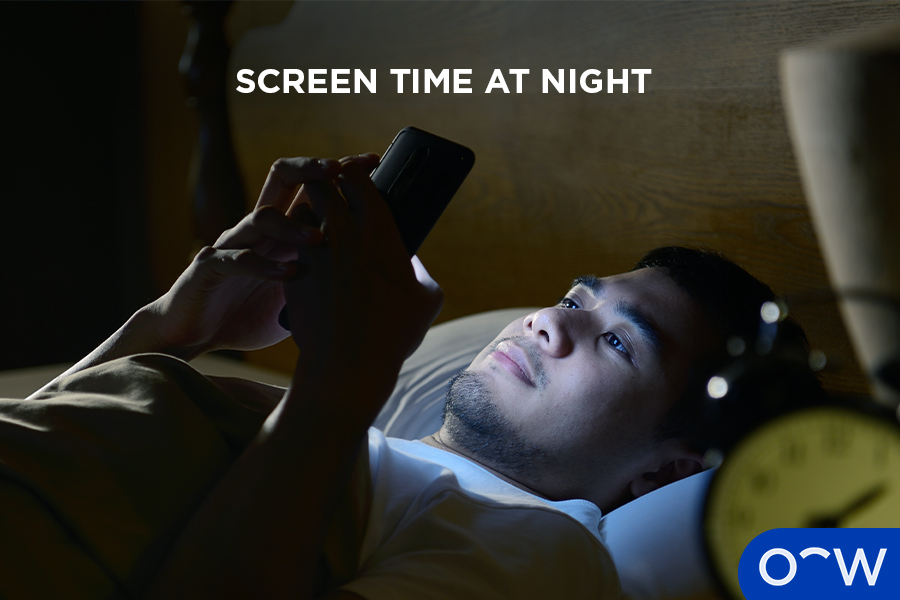 A man lying in bed looking at a smartphone.