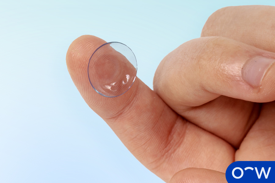 A disposable contact lens resting on a finger.