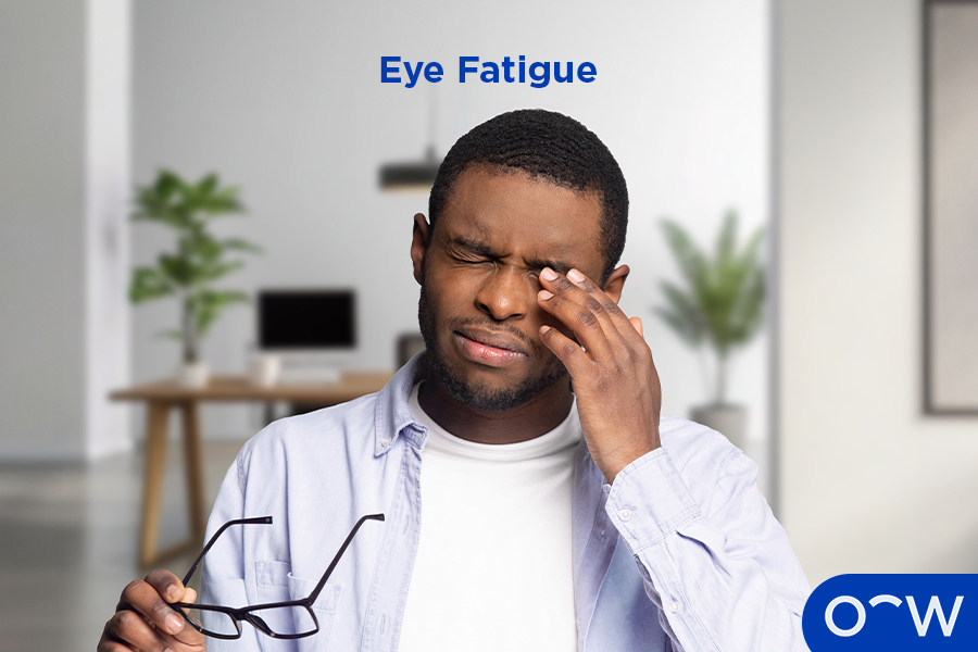 A man holding glasses experiencing eye fatigue.