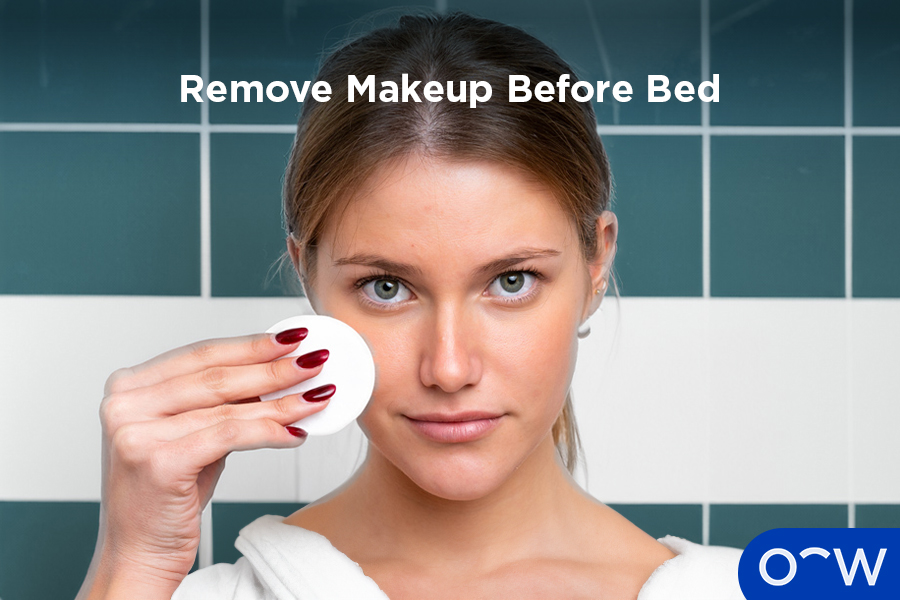 A woman removing makeup with a cotton pad.