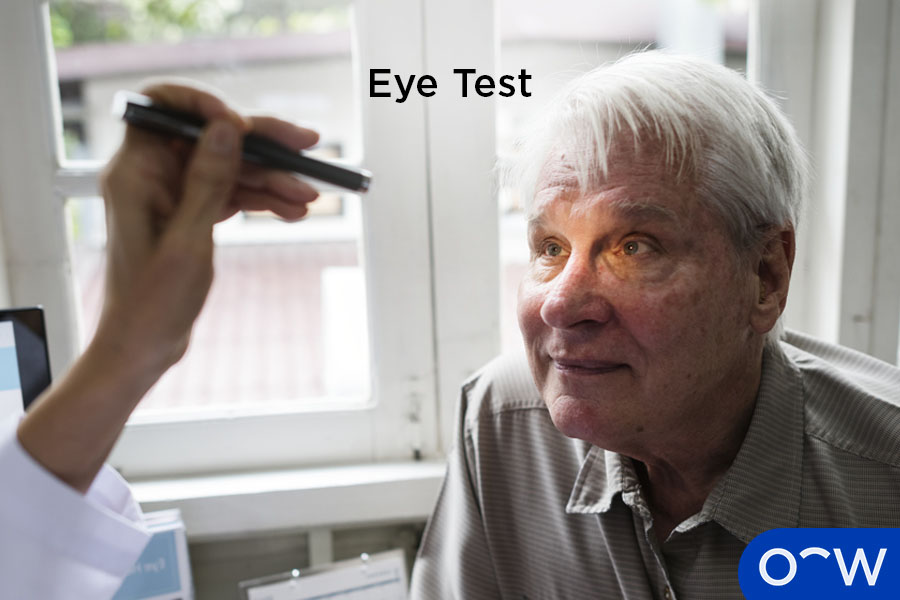 An optometrist checking elderly patient’s eyes with a handheld tool.