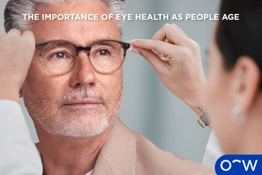 An optometrist putting glasses on an elderly man.