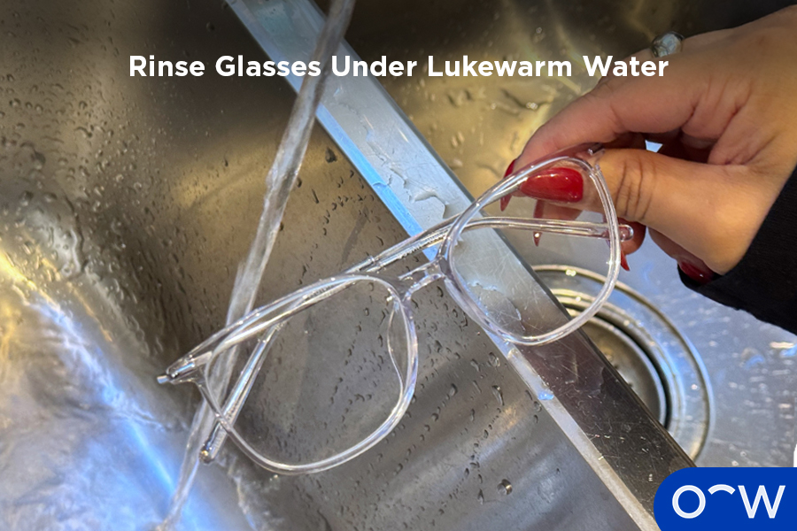 A photo of glasses being rinsed under lukewarm water.