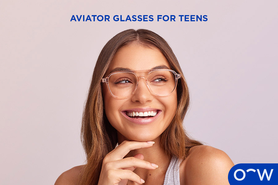 A young woman smiling at the camera wearing aviator glasses.
